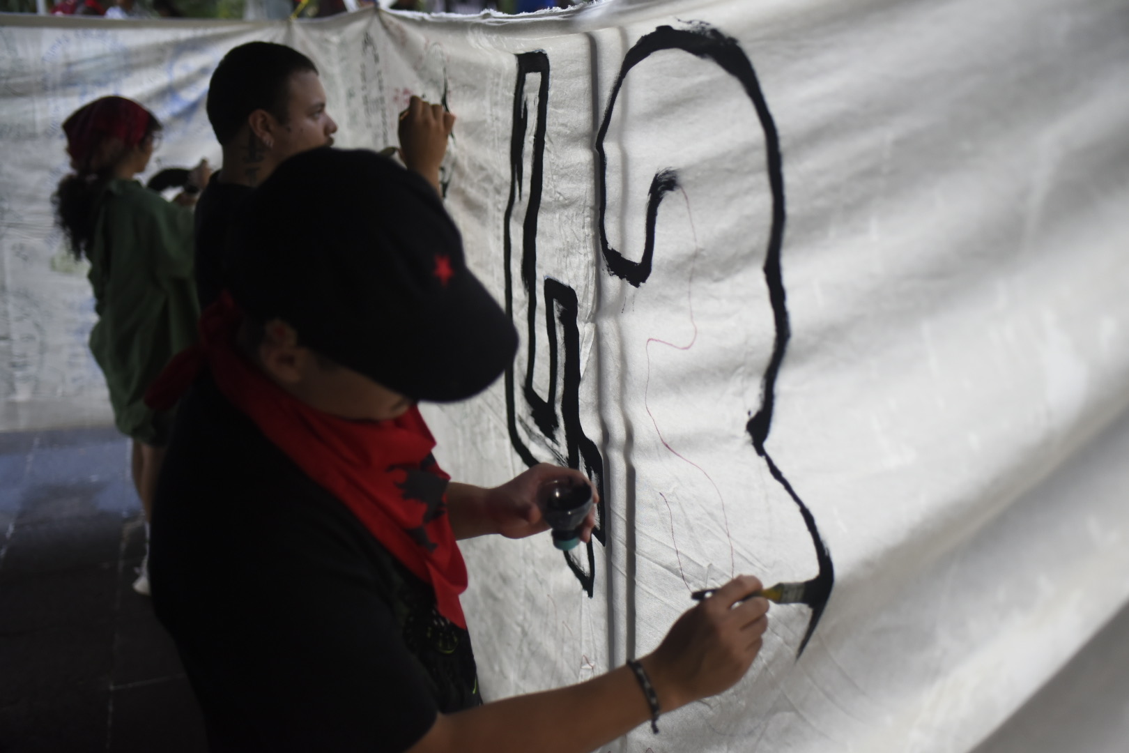 Jóvenes pintan manta de los 43 de Ayotzinapa en Xalapa a 12 años de su desaparición
